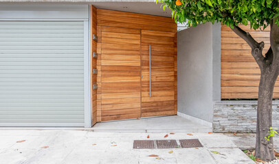 modern house entrance natural wood door by the sidewalk and tree