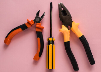 Two  nippers and screwdriver on a pink background. Layout of carpentry tools. Set of hand building tools.