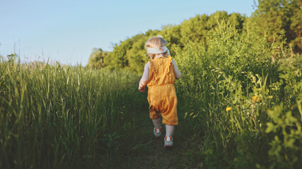 Child girl walking through the grass baby first steps milestones outdoor family vacations travel summer season nature