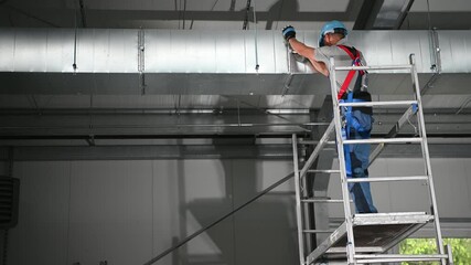 Poster - Caucasian Male Hvac Contractor Fastening Metal Clamps On Air Conditioning Shaft Assembled On Ceiling. 