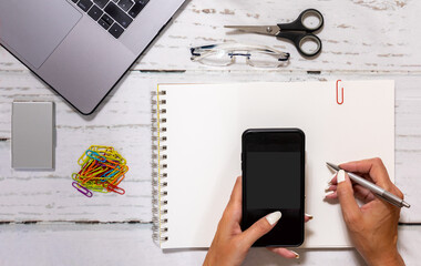 Top view of businesswoman hands using smartphone mockup at  office desk. Blank screen mobile phone for graphic display montage