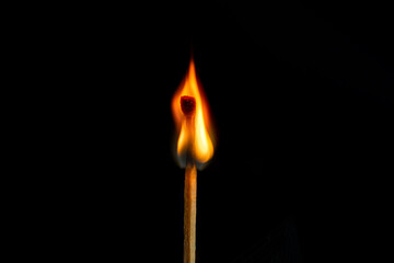 Low key, burning matchstick on black background, macro