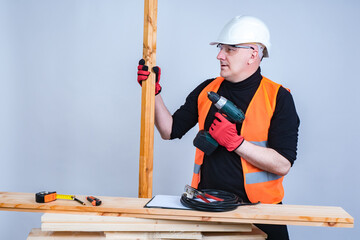 Poster - Carpenter works with wood. Builder is holding an electric screwd