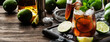 Cuba libre or rum cola cocktail with strong alcohol, lemon juice, lime and ice, dark background, steel bar tools, copy space