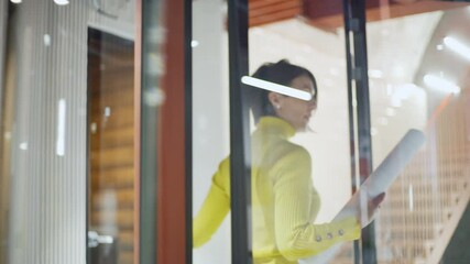 Wall Mural - Tracking shot of confident business woman walking downstairs, entering office and presenting printout with website interface templates for different devices to colleagues sitting at desk in office