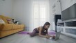 © stanis88 - On-line work out woman using internet services with help of her instructor. Portrait of a beautiful slim sporty woman practicing yoga on a mat. Woman uses notebook after exercises