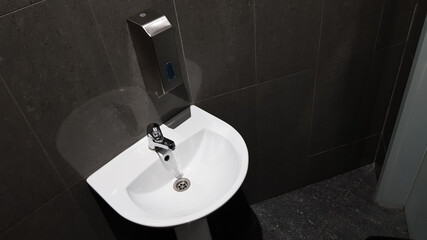 white ceramic washbasin with chrome faucet in the toilet with gray tile