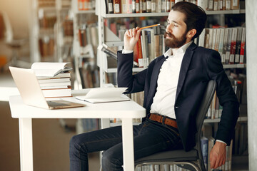 Wall Mural - Man in a library. Guy in a black suit. Student with a books.