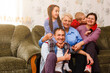 © Angelov - Grandmother and grandchildren sitting together on sofa in living room