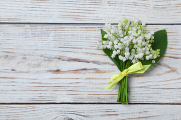  Beautiful lily of the valley flowers on white wooden table, top view. Space for text