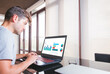 © GENETTICA - Young man working on laptop with business graphics on the screen