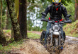© Cavan Images - man riding his scrambler type motorcycle through forrest