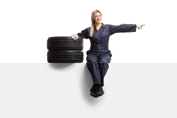 Sticker - Female auto mechanic sitting on a panel with tires and pointing to the side