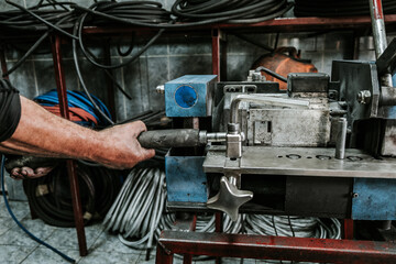 Wall Mural - Close up shot of manual worker hands. Factory for industrial production of hydraulic hoses.