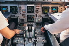 Back View Of Crop Anonymous Male Captain And Pilot Sitting In Cockpit Of Modern Airplane And Checking Equipment While Preparing For Departure