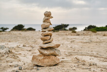 Stones Placed On Each Another On Empty Sandy Ground On Calm Seashore On Overcast Day In Ibiza