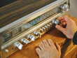 © Cien X Cien Studio/ADDICTIVE STOCK - High angle of crop hands of unrecognizable male tuning radio placed on wooden shelf in living room