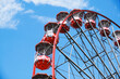 © Cien X Cien Studio/ADDICTIVE STOCK - From below of Ferris wheel with red cabins located on amusement park on sunny day with blue sky