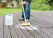 A man cleans the terrace. Ecological detergents, foam and water on the boards. Canister with detergent.