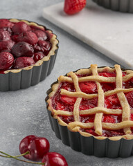 vegan tartlets with cherries and strawberries on a light gray background and marble board