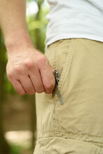 A Man Taking A Pocket Knife Out Of His Pocket.
