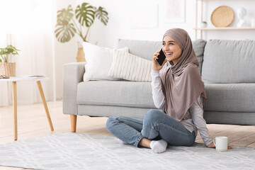 Wall Mural - Free Time. Joyful Muslim Girl Talking On Cellphone With Friend At Home