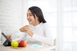 © anon - Young asian woman and happy   eating healthy salad sitting on the table with green fresh ingredients indoors.greens in bowl for breakfast or lunch. Vegan vegetarian healthy food.