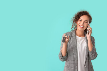 Poster - Happy young woman with key talking by phone on color background