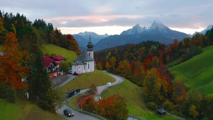 Wall Mural - 4k drone forward video (Ultra High Definition) of Maria Gern church with Hochkalter peak on background. Wonderful autumn sunset on Bavaria Alps. Majestic evening landscape of Germany countryside.