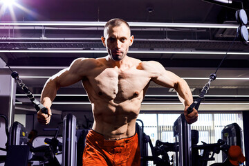 Handsome young male bodybuilder in gym. Big strong man during training in the gym. Guy with big muscles who is an athlete, trainer or instructor