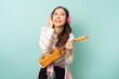 Young asian woman using headphones while playing ukulele with happy. People lifestyle concept.
