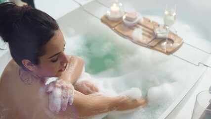 Wall Mural - Smiling woman washing hands with foam. Sexy girl relaxing in bath with candles