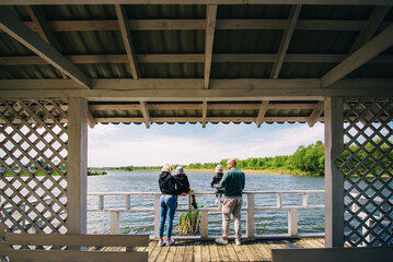 Happy family standing on a wooden jetty. Rear view