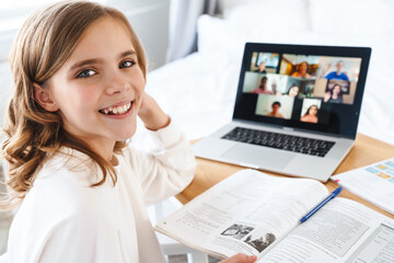 Poster - Photo of girl writing in exercise book while studying online