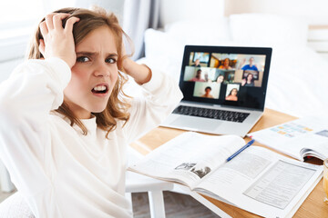 Canvas Print - Photo of displeased girl grabbing her head while studying online