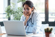 © nenetus - Smiling female doctor working with her laptop in the consultation.