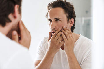 Wall Mural - Attractive young man standing in front of the bathroom mirror