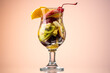 fruit salad of fresh fruits and berries in a transparent glass on a gradient background