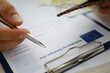 © H_Ko - Close-up of male person filling application form for schengen visa holding silver pen. Writing personal information on paper. Travelling abroad or immigration concept