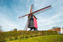 Traditional Red Wooden Windmill Against Blue Sky