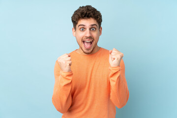 Wall Mural - Caucasian man isolated on blue background celebrating a victory in winner position