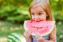 Child Eating Watermelon In The Garden. Kids Eat Fruit Outdoors. Healthy Snack For Children. 2 Years Old Girl Enjoying Watermelon.