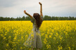 © Stepan - Young woman in sleeveless dress enjoying sunlight and nature on yellow blooming rapeseed field