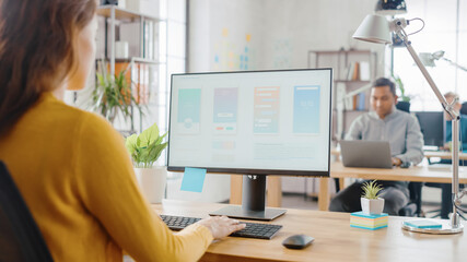Poster - Over the Shoulder: Female Mobile Software Developer Sitting at Her Desk Using Desktop Computer with Screen Showing Smartphone Application UI / UX. Office With Diverse Team of Professionals Working.