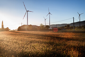 Four Wind Turbines in the Sunset in a Field and next to a Farm