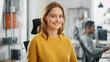 © Gorodenkoff - Portrait of Beautiful Young Woman with Red Hair Wearing Yellow Sweater Chats with Colleague and Turns Smilingly at Camera. Successful Woman Working in Bright Diverse Office.