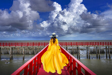 Asian Women Wear Yellow Dresses, Walking On Red Wooden Bridges Red Bridge Is A Popular Sea Viewpoint In Samut Sakhon Province, Thailand