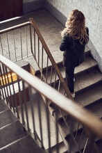 Photo Of A Woman With Long Blonde Curly Hair Dressed In A Black Suit Climbs The Stairs