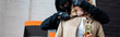 Panoramic crop of robber in balaclava holding knife near female neck during robbery
