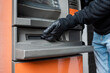 © LIGHTFIELD STUDIOS - Cropped view of burglar in leather glove holding hand near cash dispenser of automated teller machine